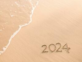 2024 año escrito en el playa en el puesta de sol tiempo. nuevo año 2024 concepto foto