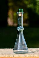 a glass flask with a green lid sitting on a wooden table photo