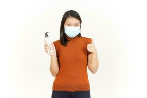 Wearing Medical Mask and Holding Hand Sanitizer Of Beautiful Asian Woman Isolated On White photo