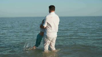 padre giochi con il suo figlio mentre nuoto nel il mare. video