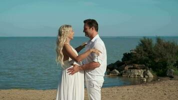 Husband and pregnant wife hugging standing on the ocean. video