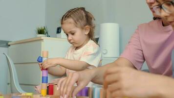 Mom and children build structures from wooden blocks at home. video