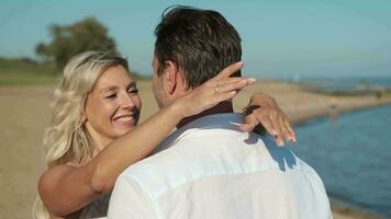 A man and woman in love hugging while standing on the ocean during their honeymoon. video