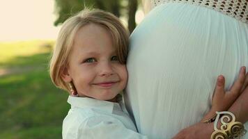 The child kisses and strokes the belly of a pregnant mother. video