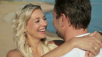 A man and woman in love hugging while standing on the ocean during their honeymoon. video