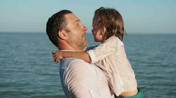 Wet father and son are fooling around standing near the ocean. video