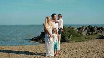 A happy family with a pregnant mother are standing on the ocean. video