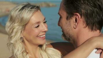 A man and woman in love hugging while standing on the ocean during their honeymoon. video