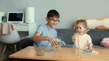 niños jugar con un metal constructor a el mesa a hogar. video