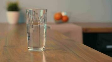 The hand takes a glass of clean water that is on the kitchen table. video