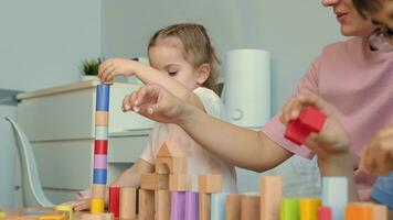 Mom and children build structures from wooden blocks at home. video