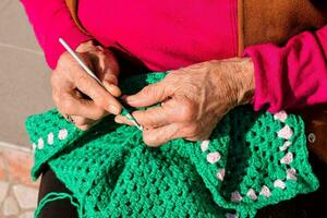 an older woman is knitting a green crocheted blanket photo