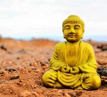 a golden buddha statue sitting on top of a dirt field photo