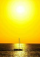 a sailboat is in the middle of the ocean at sunset photo