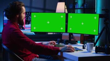 Photographer using photo editing software on Chroma key multi monitors setup to improve images quality. Photo editor utilizing pictures retouching application on green screen display video