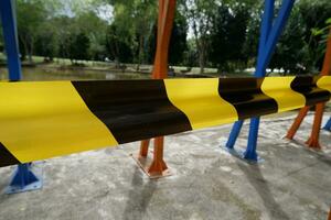 cinta o barricada con negro amarillo rayas con desenfocado lago antecedentes. concepto ilustración de un persona ahogo en un lago foto