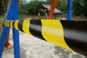 ribbon or barricade with black yellow stripes with defocused lake background. concept illustration of a person drowning in a lake photo