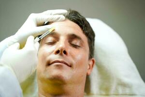 Closeup hands of cosmetologist in medical grove holding a syringe injecting serum on customer's face. Beauty skin concept. photo