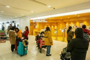 Sapporo City, Japan, 2018 - Group of Chinese tourist waiting for their friends ask a information trip at Hokkaido Tourist Information Center in New Chitose Airport. photo