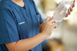 A veterinarian is preparing a saline syringe to clean the wound of a dog receiving treatment in clinic. photo