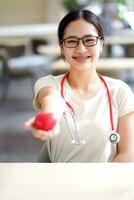 médico estudiante acción dar un caucho rojo corazón en borroso antecedentes. asiático médico estudiante con corazón enfermedad concepto. foto
