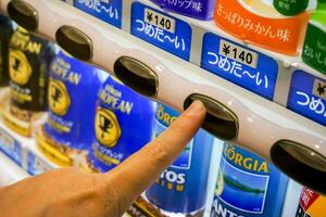 Osaka City, Japan, 2018 -Hand of one people pressing to buy canned soft drink from Japan vending machine. photo