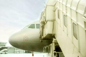 Closeup jet bridge and white airplane parked on airport ground and winter blue sky background. photo