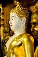 Closeup and side view ancient golden Buddha statue of Burmese art in sanctuary at Wat Phra That Hariphunchai Lumphun Thialand. photo