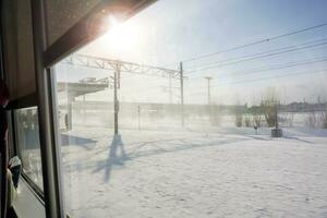 Outside the train when looking from train windows. Can see electric pole beside railroad and winter snow with sun light on blue sky background. photo