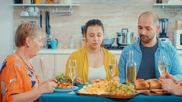 mujer hablando durante cena. multi generación, cuatro gente, dos contento parejas que se discute y comiendo durante un gastrónomo comida, disfrutando hora a hogar, en el cocina sentado por el mesa. foto