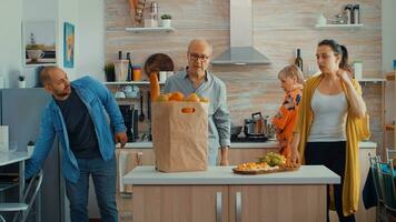 Man returning from market with fruits and bread. Young couple coming from shopping bringing a paper bag with groceries, fresh food, from supermarket at parents home to prepare a family dinner photo