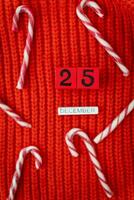 Christmas candies lie on a red plaid along with wooden letters and numbers December 25th. Christmas decoration on a bright background. photo