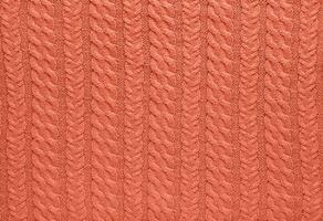 Texture of smooth knitted sweater with pattern. Handmade knitting wool or cotton fabric texture. Background of Large knit pattern with knitting needles or crochet. Peach Fuzz colour of 2024 year photo