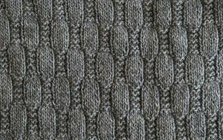 Background with gray knitted leaf shape, knitting pattern with cables. Top view, close-up. Handmade knitting wool photo