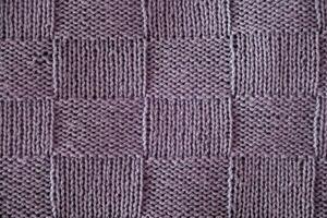 Unusual abstract knitted chess pattern background texture. Top view, close-up. Handmade knitting wool photo