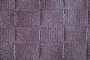 Unusual abstract knitted chess pattern background texture. Top view, close-up. Handmade knitting wool photo