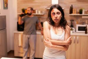 Abused woman being depressive and trembled because of husband agression. Violent aggressive man sing injuring terrified helpless, vulnerable, afraid, beaten and panicked wife, victim. photo