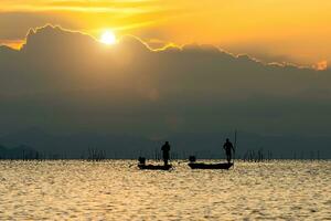 silueta pescador y puesta de sol cielo en el lago. foto