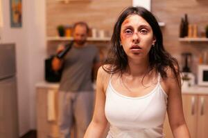 Vulnerable woman after being beaten and traumatised by violent drunk husband. Violent aggressive man abusing injuring terrified helpless, vulnerable, afraid, beaten and panicked wife. photo