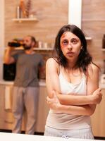 Abused wife being afraid of husband. Couple with serious domestic violence. Violent aggressive man abusing injuring terrified helpless, vulnerable, afraid, beaten and panicked woman, victim. photo