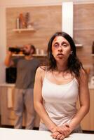 Portrait of hopeless abused wife in front of drunk husband agression. Violent aggressive man abusing injuring terrified helpless, vulnerable, afraid, beaten and panicked woman, victim. photo