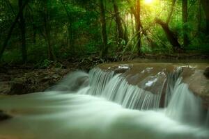 Small waterfall in the dark forest with light. photo