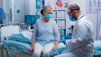 Retired old woman wearing protection mask signing for discharge. Modern private hospital or clinic. Healthcare medical physician consultation during COVID-19 global crisis, healthcare problem photo