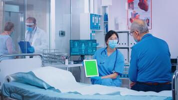 Nurse presenting green screen tablet to patient in modern private hospital. Isolated mockup chroma replacement screen on gadget for your app, text, video or digital assets. Easy keying medicine medical related theme photo