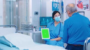 Patient looking at green screen digital tablet in modern private hospital or clinic. Isolated mockup chroma replacement screen on gadget for your app, text, video or digital assets. Easy keying medicine medical related theme photo