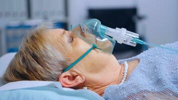 Close up portrait of retired woman breathing with difficulties in oxygen mask lying in hospital bed during covid-19 coronavirus outbreak. Medical medicine healthcare system. Infection treatment photo