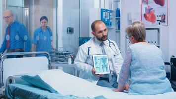 Doctor giving bones disease consultation for elderly patient, explaining osteoporosis on digital tablet PC. Health care in private clinic or modern hospital, old woman consultation senior illness photo