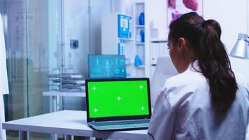 salud facultativo utilizando ordenador portátil con croma llave en privado clínica vistiendo blanco Saco mientras enfermero en azul uniforme comprobación paciente resultados en computadora. foto