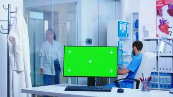 Doctor arriving in health clinic with computer having chroma key on display. Desktop with blank and copy space available on display of medicine specialist in clinic cabinet. photo