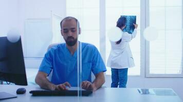 médico y asistente mirando a paciente radiografía imagen en hospital gabinete. médico examinando paciente radiografía antes de dando un tratamiento a cura su afecto. foto